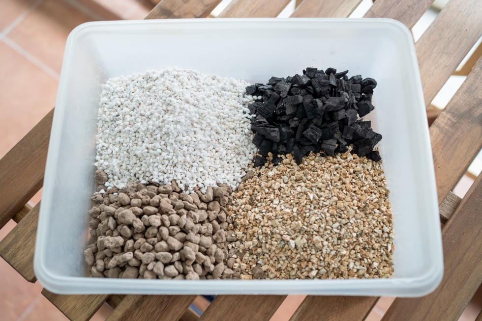 Potting soil-Potting mix-a square glass dish with small separate piles of pumice, perlite, charcoal, vermiculite.