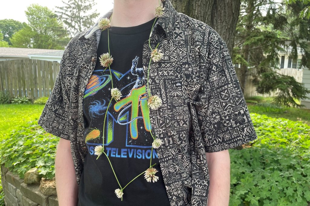 Young man wearing a clover flower chain necklace.