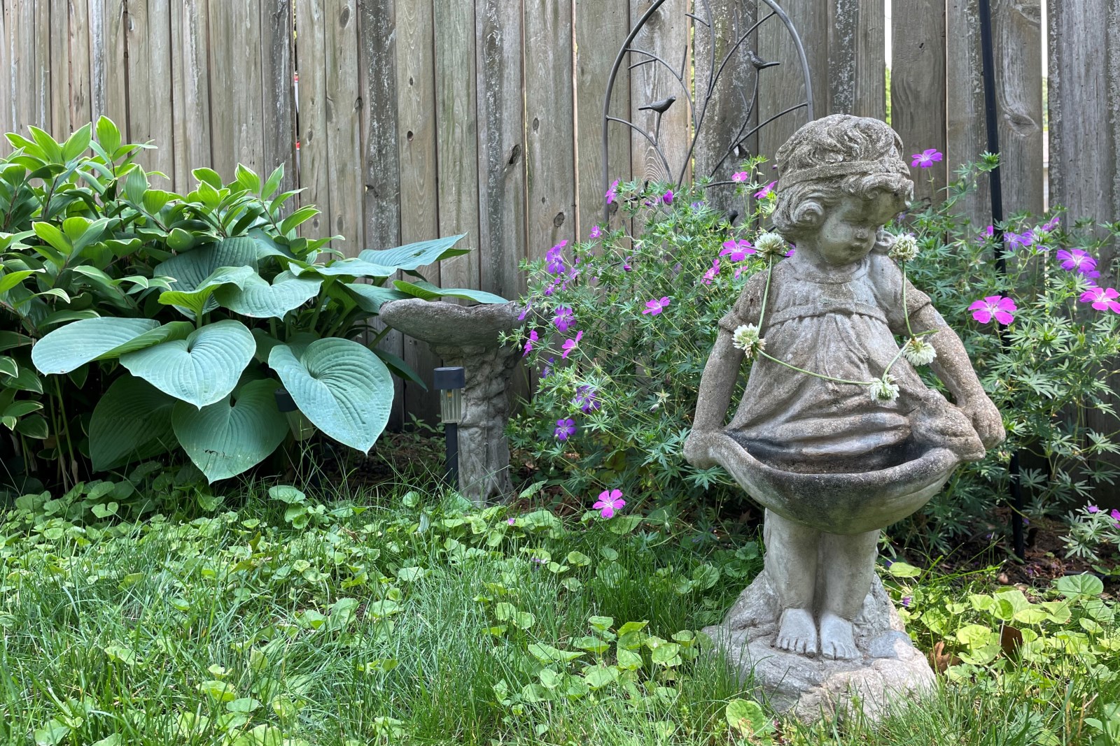 Garden statue-4 A charming concrete figure of a young girl decorated with a clover flower chain necklace.